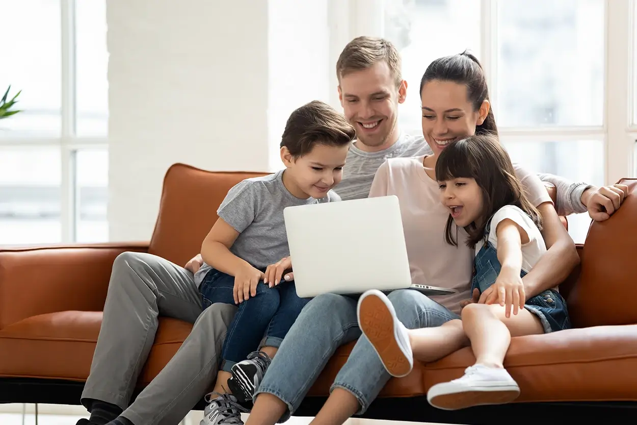 Junge Familie auf dem Sofa mit Laptop
